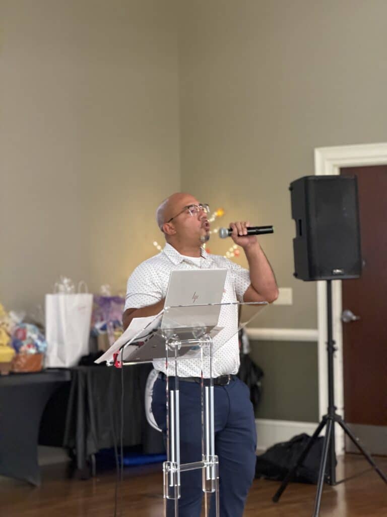 Man in a white shirt speaking into a microphone at a podium