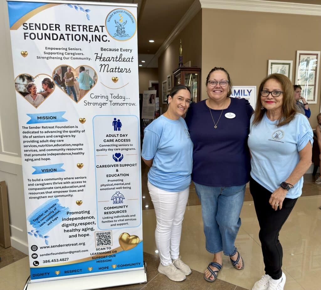 Three women standing beside a Sender Retreat Foundation banner