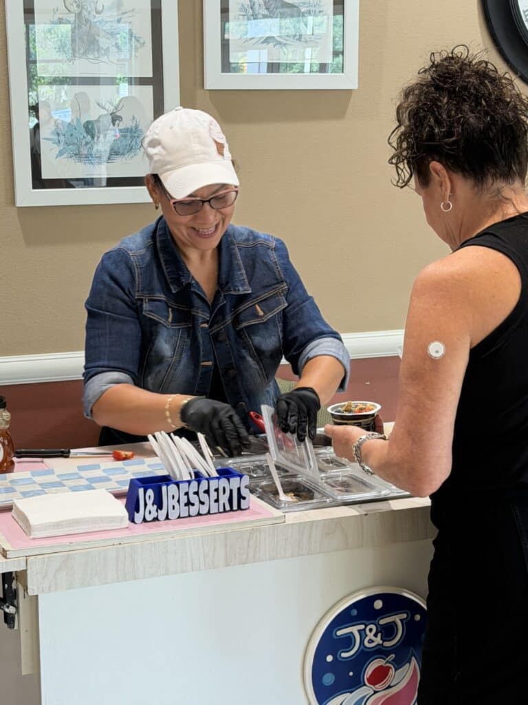 Woman in a denim jacket serving desserts at a vendor table