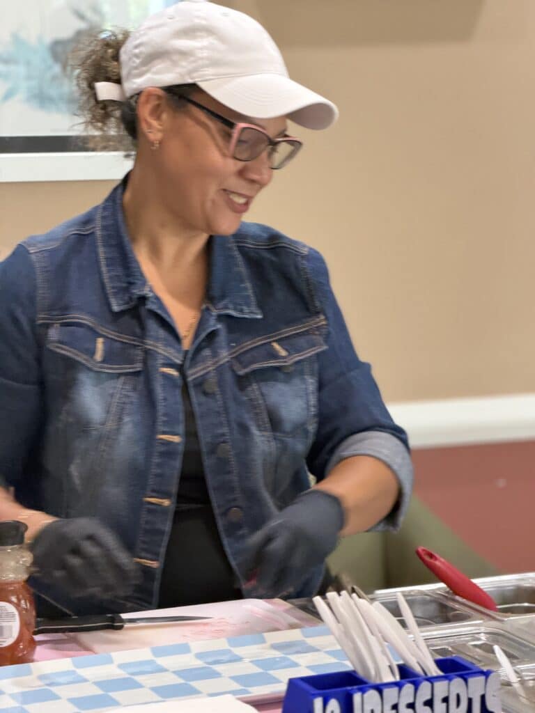Woman in a white cap and denim jacket serving food