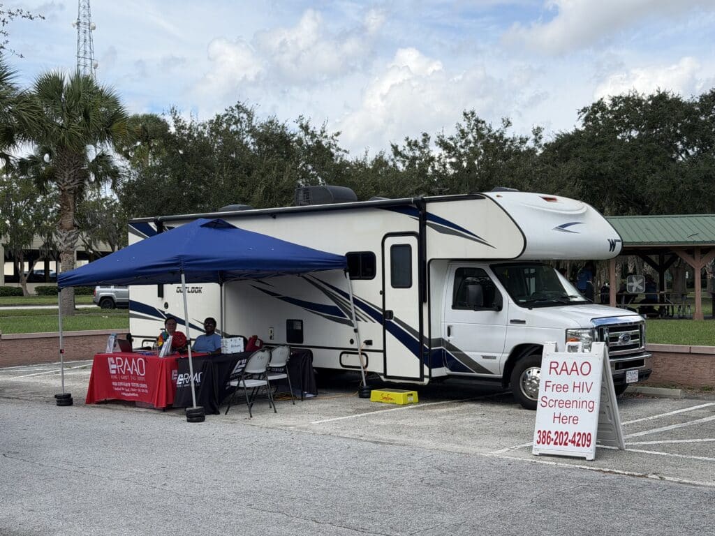 Mobile health screening RV with a blue canopy outdoors